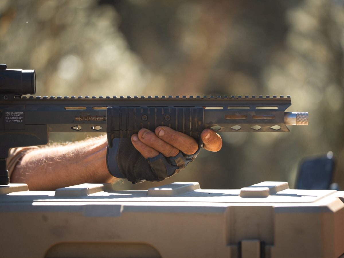 Gloved hand supporting a rifle handguard resting on an esky in the field