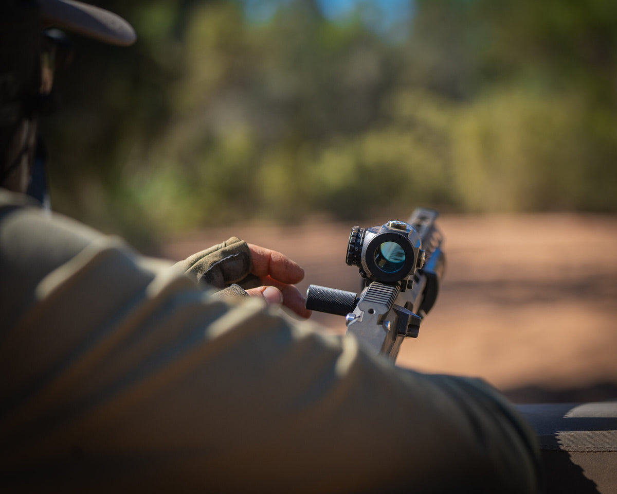 Hand adjusting the elevation turret on a rifle scope