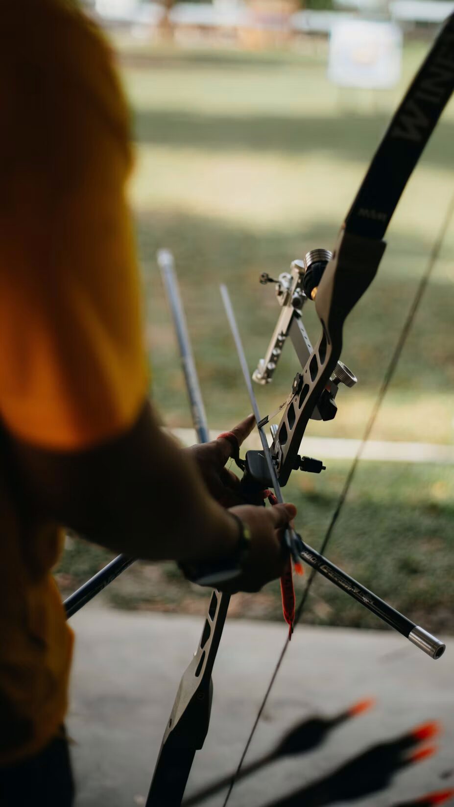 Archer nocking an arrow on a recurve bow at a target range