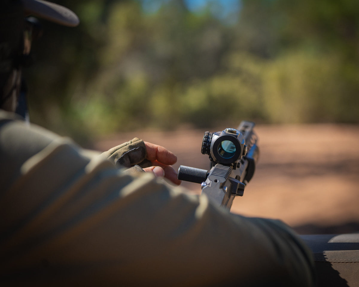 Hand adjusting the elevation turret on a rifle scope